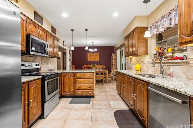 kitchen with decorative backsplash, kitchen peninsula, a notable chandelier, pendant lighting, and appliances with stainless steel finishes