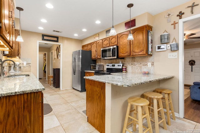 kitchen with decorative backsplash, light stone countertops, stainless steel appliances, and sink