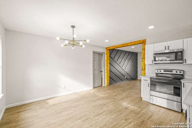 kitchen featuring white cabinets, appliances with stainless steel finishes, light hardwood / wood-style floors, and hanging light fixtures