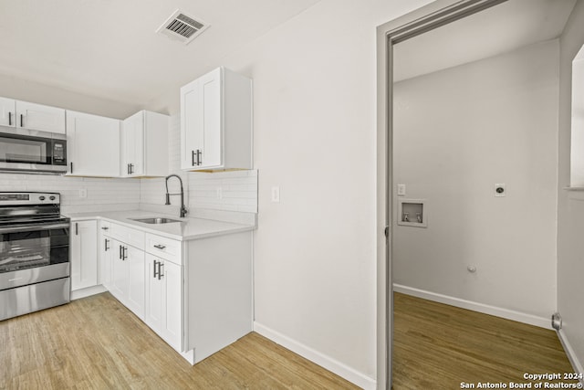 kitchen with white cabinetry, sink, stainless steel appliances, decorative backsplash, and light wood-type flooring