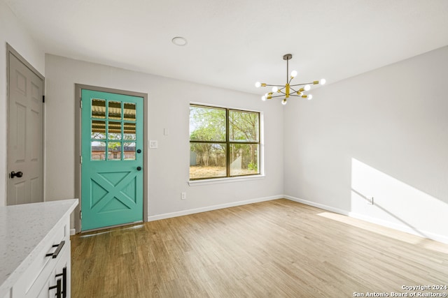 unfurnished dining area with hardwood / wood-style flooring and a notable chandelier