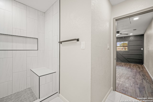 bathroom featuring hardwood / wood-style flooring, ceiling fan, and a tile shower