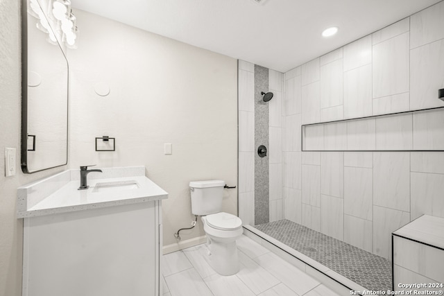 bathroom with a tile shower, vanity, and toilet