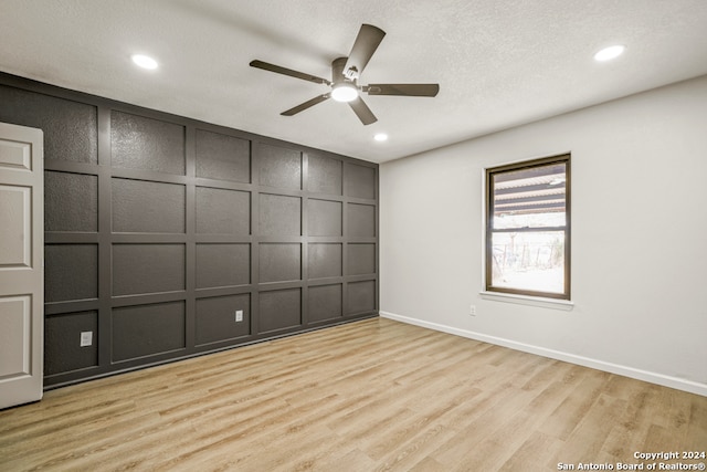 empty room with ceiling fan, light hardwood / wood-style floors, and a textured ceiling