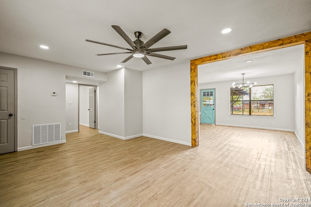 empty room with ceiling fan with notable chandelier and light wood-type flooring