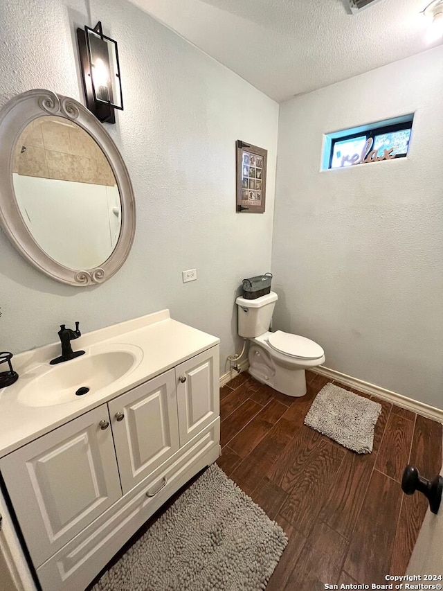 bathroom featuring vanity, toilet, hardwood / wood-style flooring, and a textured ceiling