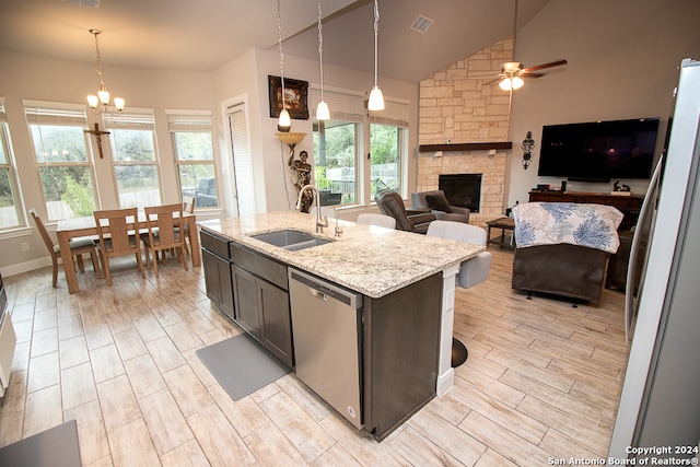 kitchen with stainless steel dishwasher, decorative light fixtures, a center island with sink, and a wealth of natural light