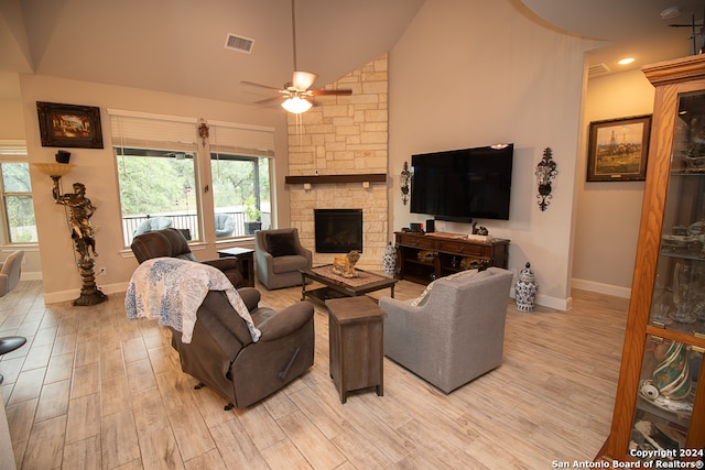 living room featuring ceiling fan, light wood-type flooring, a fireplace, and high vaulted ceiling