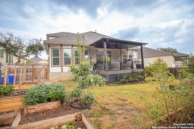 back of property with ceiling fan and a yard