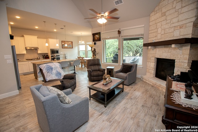 living room with a fireplace, light wood-type flooring, high vaulted ceiling, and ceiling fan