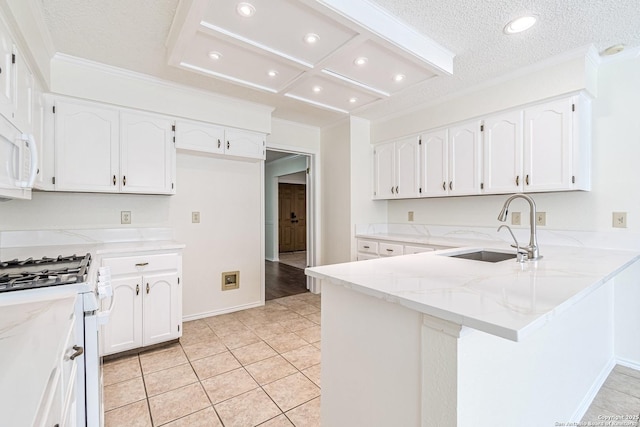 kitchen featuring kitchen peninsula, light stone countertops, white gas range oven, white cabinets, and sink