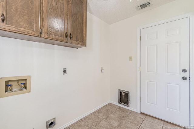 laundry area featuring electric dryer hookup, washer hookup, a textured ceiling, cabinets, and light tile patterned floors