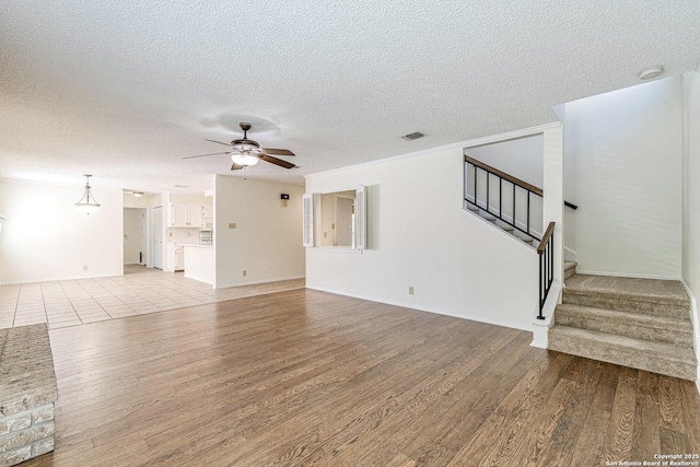 unfurnished living room featuring a textured ceiling, light wood-type flooring, and ceiling fan