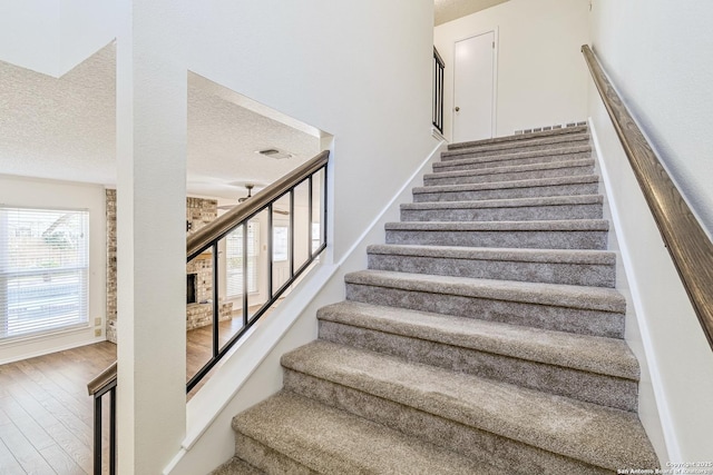 staircase with a textured ceiling and hardwood / wood-style floors