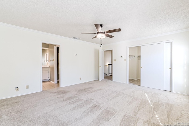 unfurnished bedroom with ceiling fan, crown molding, light carpet, and ensuite bath