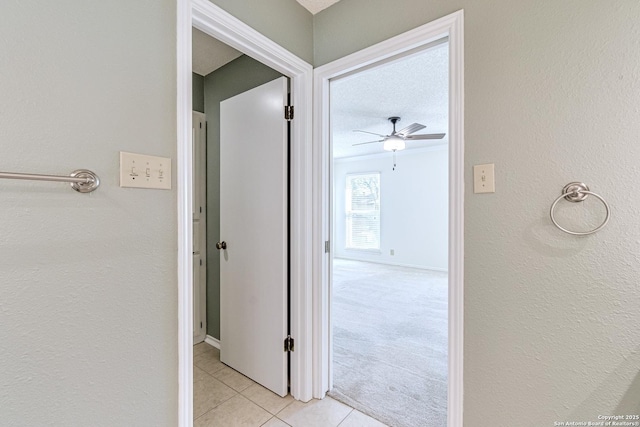 hallway with a textured ceiling and light tile patterned flooring