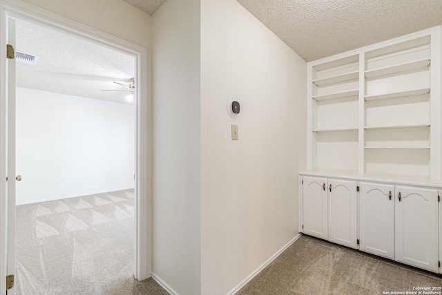 corridor featuring a textured ceiling and light carpet