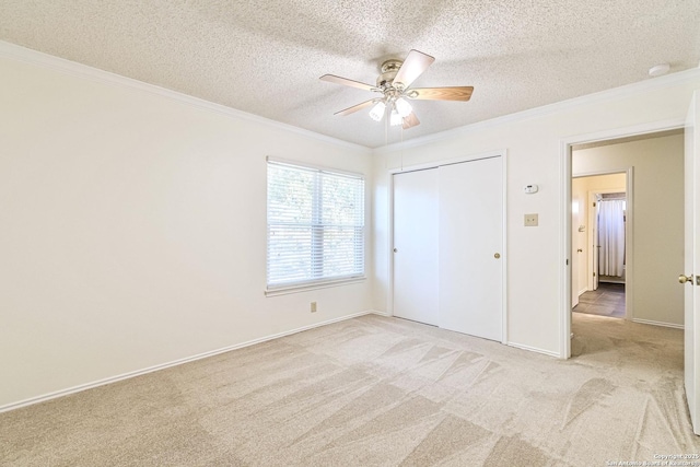 unfurnished bedroom featuring light carpet, ceiling fan, a textured ceiling, and ornamental molding