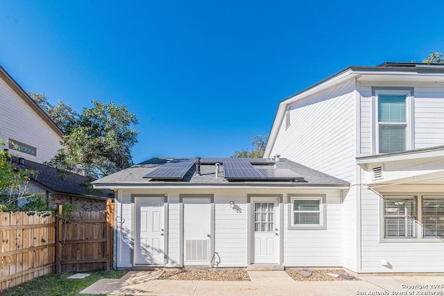 rear view of property featuring solar panels