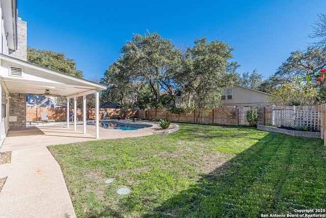 view of yard with a patio area, ceiling fan, and a fenced in pool