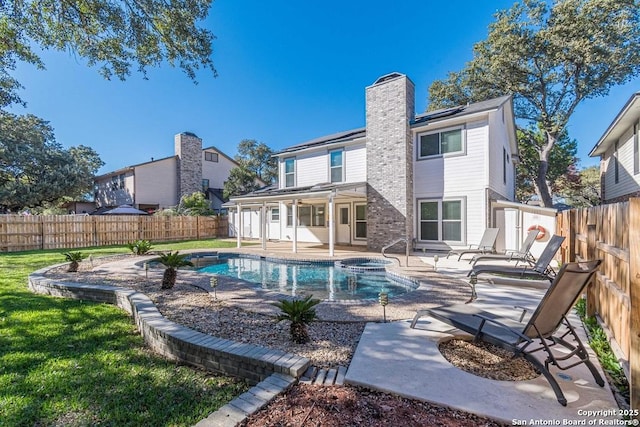 rear view of property with a patio, a swimming pool with hot tub, and solar panels