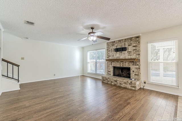 unfurnished living room with a fireplace, dark wood-type flooring, ceiling fan, and a textured ceiling