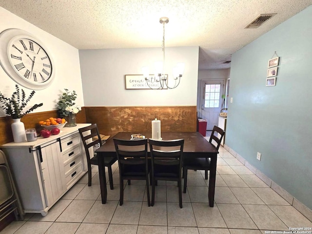 tiled dining room featuring a notable chandelier and a textured ceiling