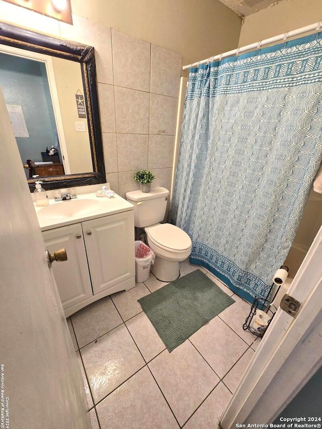 bathroom featuring a shower with shower curtain, toilet, tile patterned floors, tile walls, and vanity