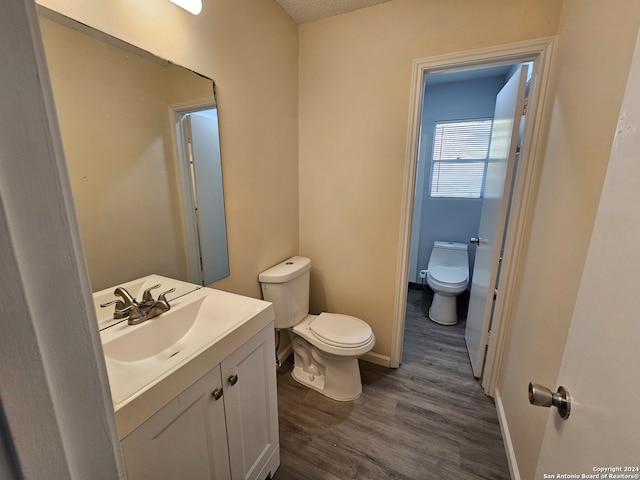 bathroom featuring vanity, a textured ceiling, hardwood / wood-style flooring, and toilet