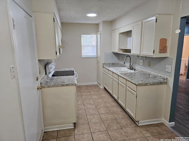 kitchen featuring white cabinetry, decorative backsplash, sink, and stove