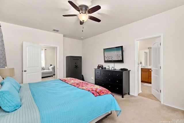 bedroom with ensuite bath, light carpet, and ceiling fan