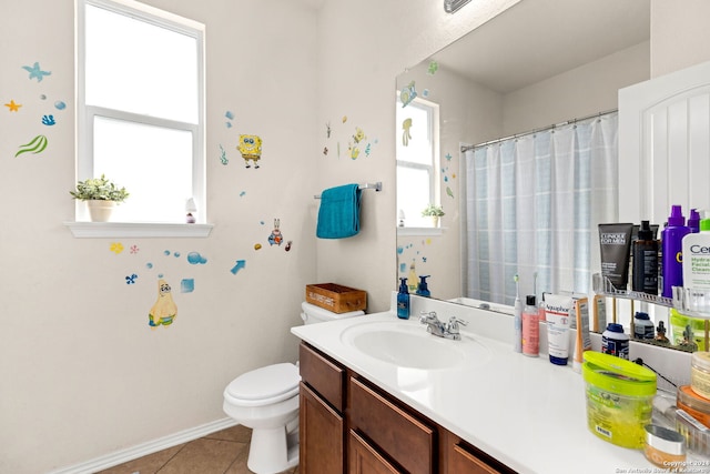 bathroom featuring vanity, toilet, a healthy amount of sunlight, and tile patterned floors