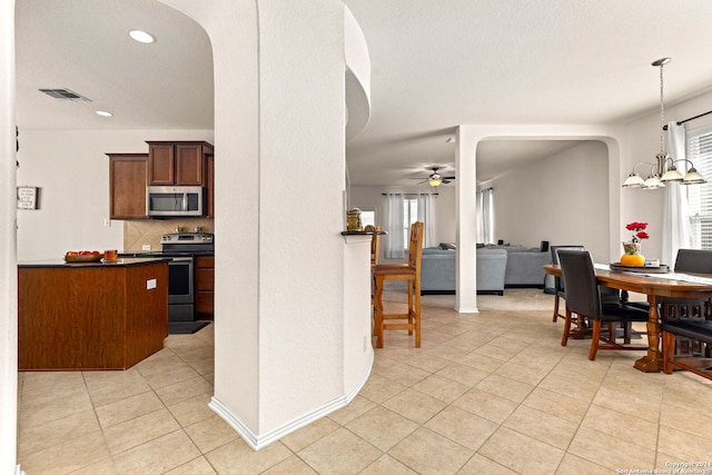 kitchen with hanging light fixtures, stainless steel appliances, ceiling fan with notable chandelier, and light tile patterned floors