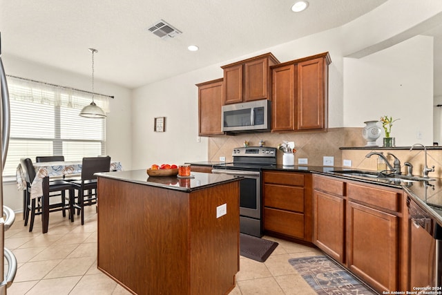 kitchen featuring hanging light fixtures, sink, a center island, appliances with stainless steel finishes, and tasteful backsplash