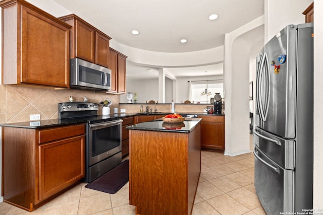 kitchen with decorative backsplash, a kitchen island, kitchen peninsula, stainless steel appliances, and light tile patterned flooring