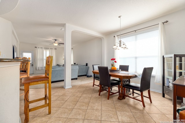 tiled dining space featuring ceiling fan with notable chandelier