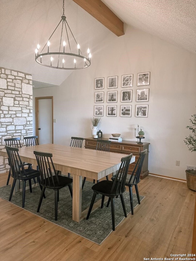 dining area with light hardwood / wood-style floors, a textured ceiling, vaulted ceiling with beams, and an inviting chandelier