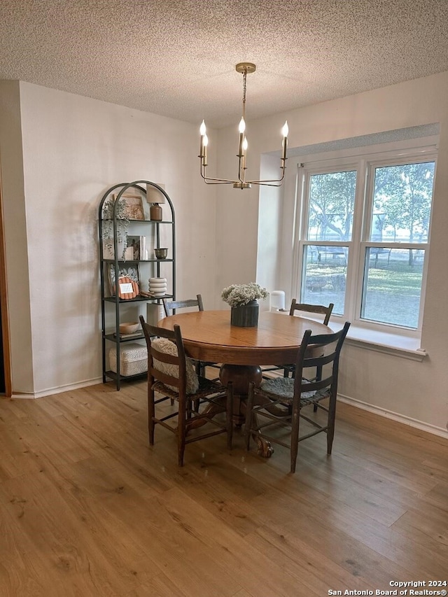 dining room featuring hardwood / wood-style flooring, a textured ceiling, and a notable chandelier