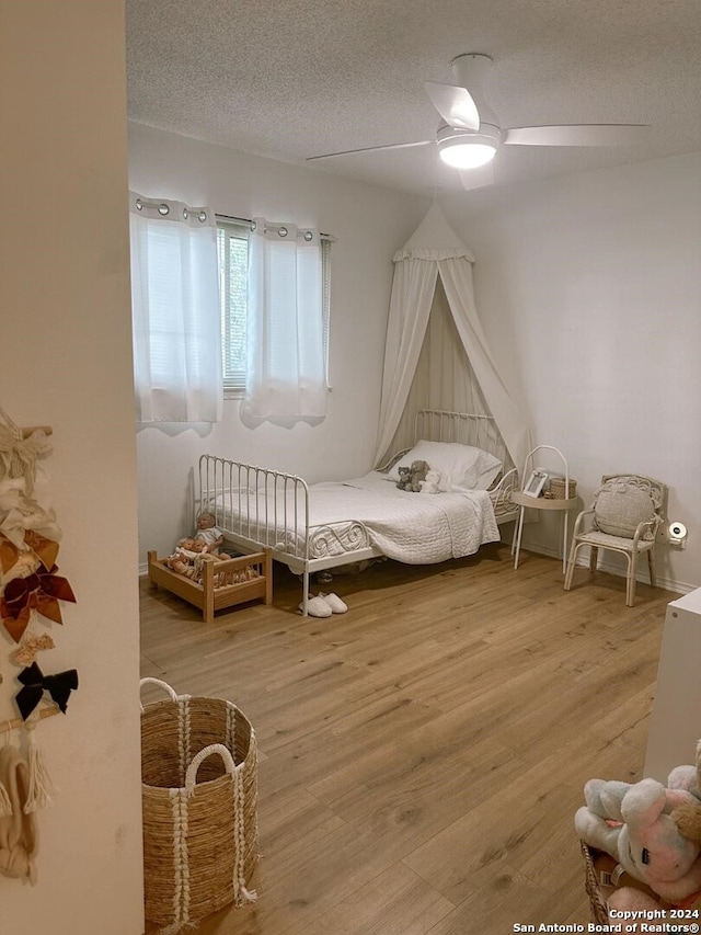 bedroom with wood-type flooring, ceiling fan, and a textured ceiling