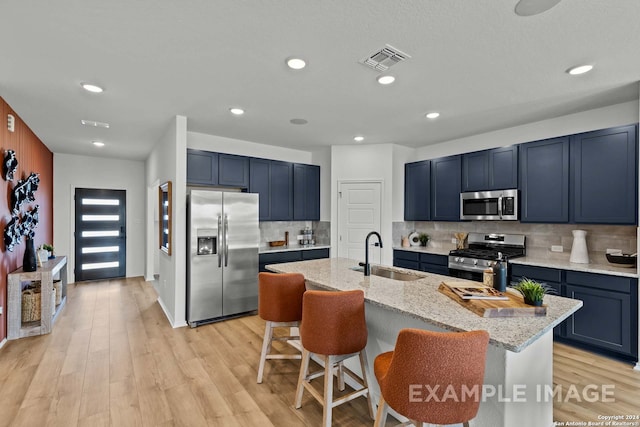 kitchen featuring a kitchen island with sink, appliances with stainless steel finishes, sink, and light hardwood / wood-style flooring