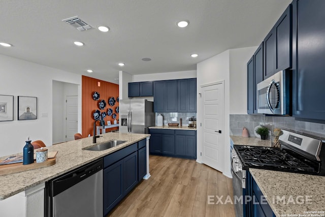 kitchen with stainless steel appliances, blue cabinetry, decorative backsplash, sink, and light hardwood / wood-style floors