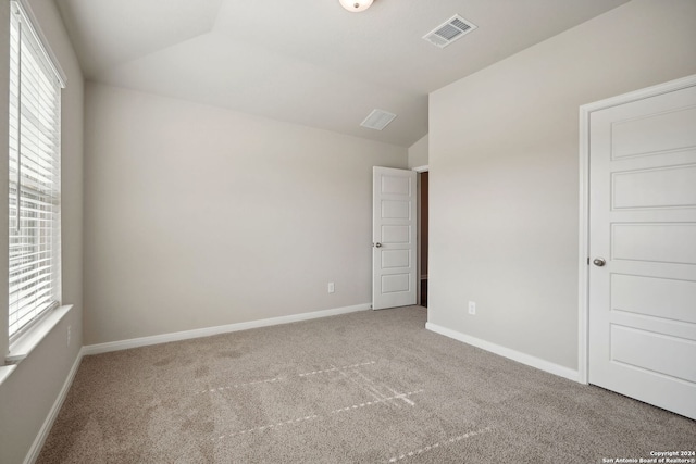 carpeted empty room featuring vaulted ceiling