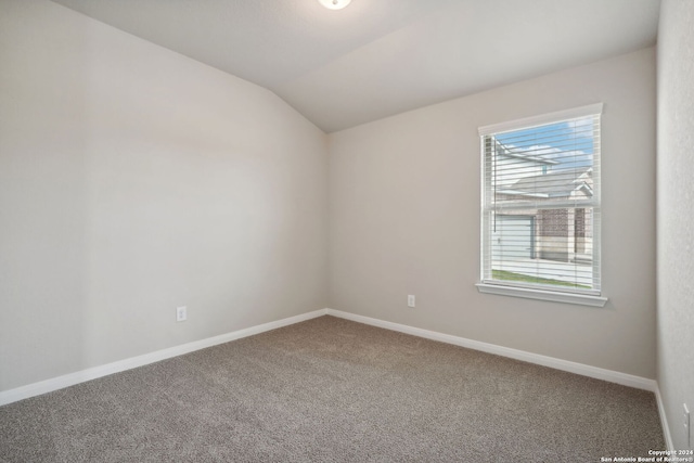 carpeted empty room featuring a wealth of natural light and vaulted ceiling