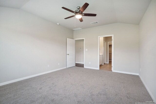 unfurnished bedroom with connected bathroom, light colored carpet, vaulted ceiling, and ceiling fan