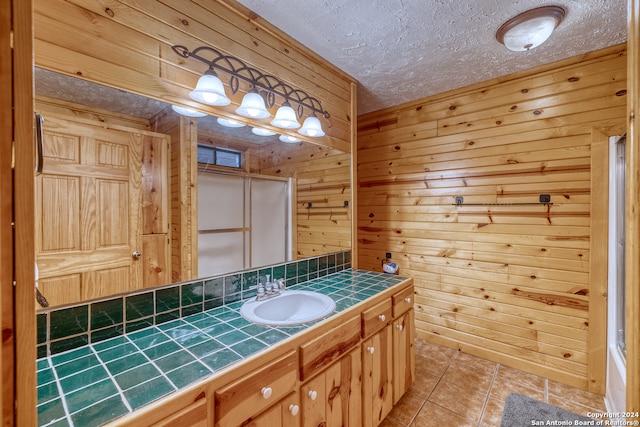 bathroom featuring vanity, wooden walls, tile patterned floors, and a textured ceiling