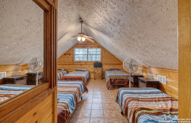 tiled bedroom featuring wood walls, ceiling fan, and a textured ceiling