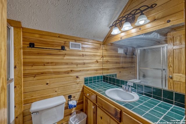 bathroom with toilet, wood walls, a textured ceiling, vanity, and walk in shower