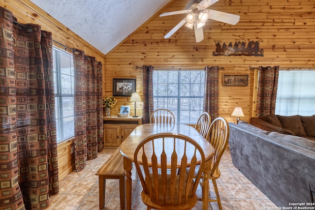 dining room with plenty of natural light, wooden walls, a textured ceiling, and high vaulted ceiling