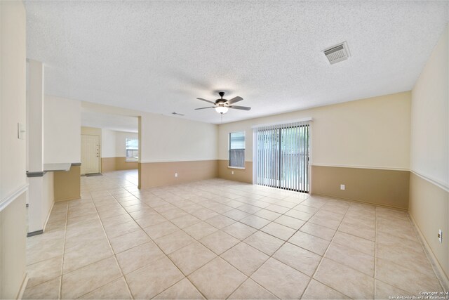 tiled empty room featuring a textured ceiling and ceiling fan