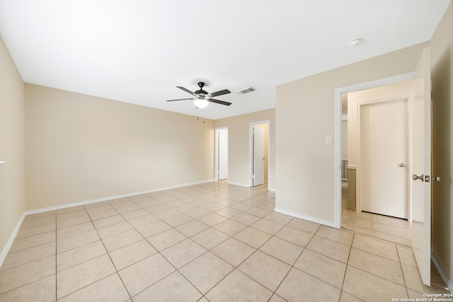 tiled empty room featuring ceiling fan and a textured ceiling